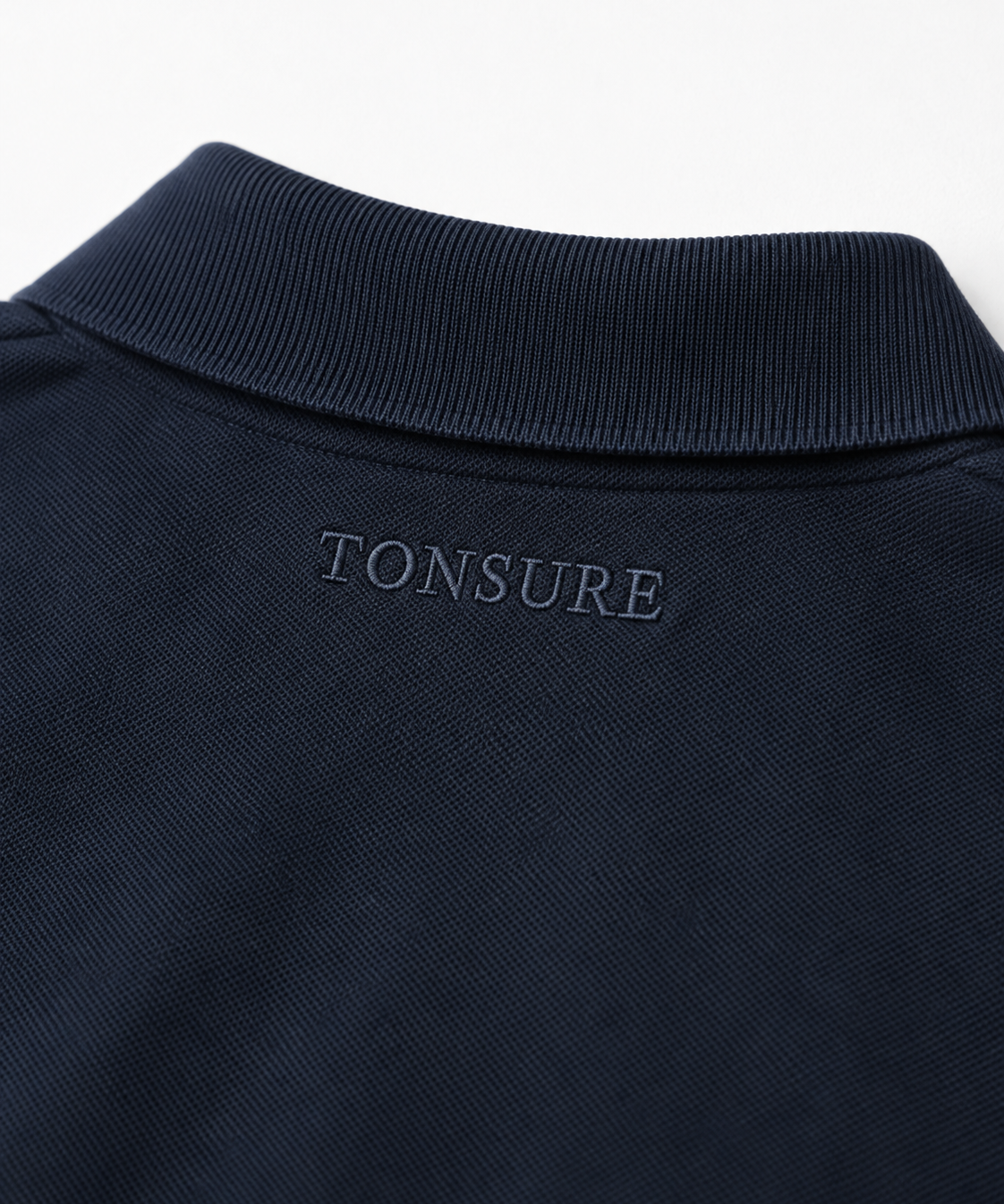 Detaljefoto af Tonsure broderi på Milton polo dark navy